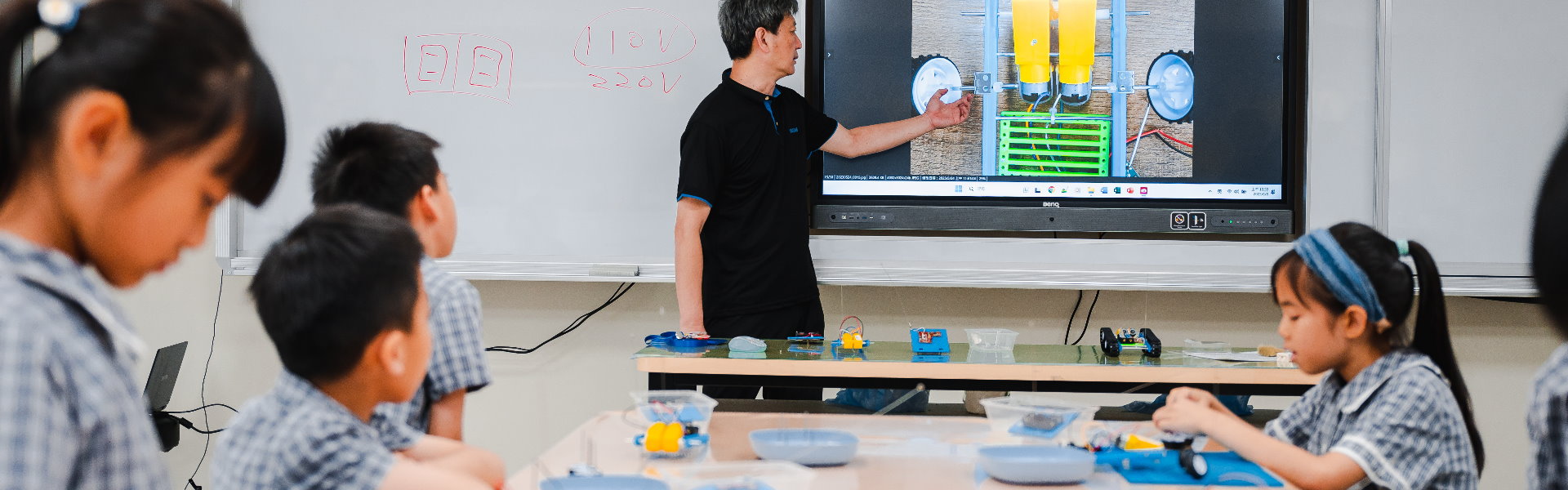 LUYA Academy students watching a teacher explain a project on a classroom screen
