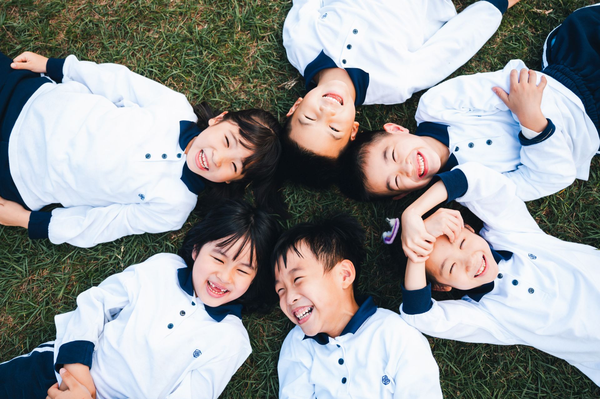 LUYA Academy students lying in a circle on the grass and smiling