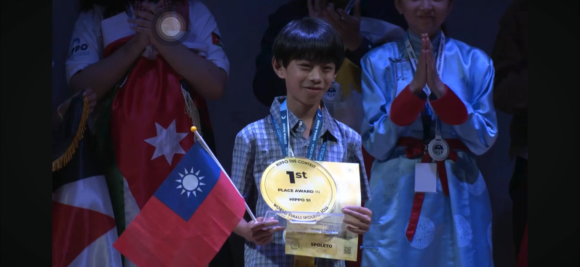 Kyle Chang on the award stage holding the HIPPO first-place trophy and certificate with a Taiwan flag, as fellow participants applaud